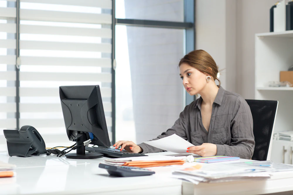 HR administrator working through employee records and files at a desk